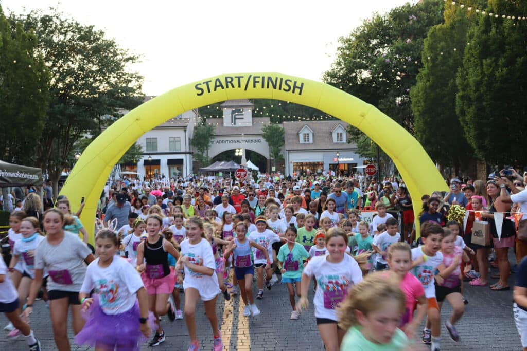 Multi-age group of runners and an inflatable start/finish arch