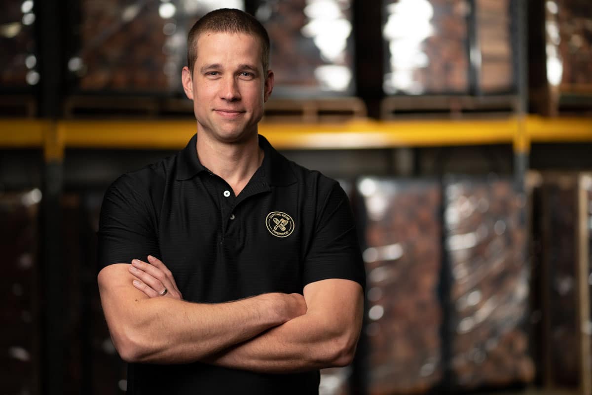 man in black shirt, arms crossed in front of him, looking at camera