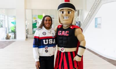 Olympic athlete standing with a school mascot