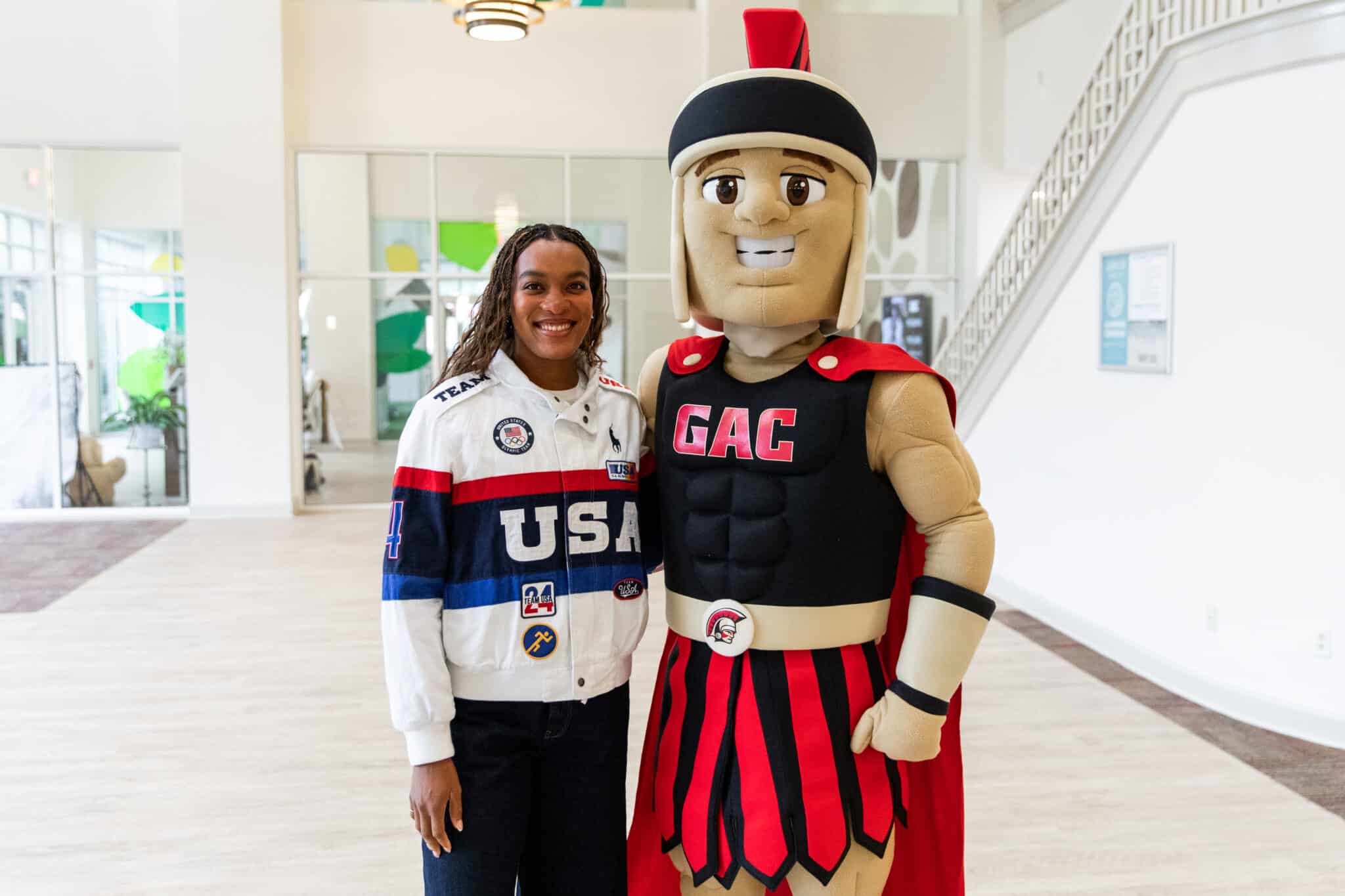 Olympic athlete standing with a school mascot