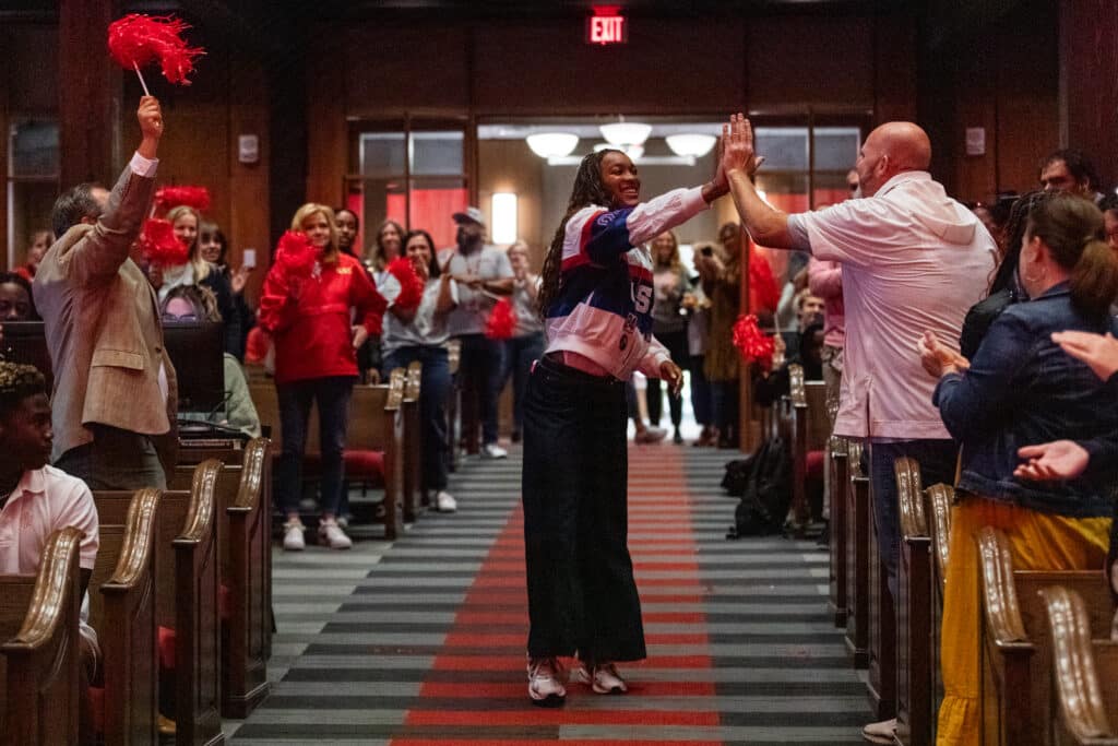 Female Olympian meeting members of the audience in a school auditorium