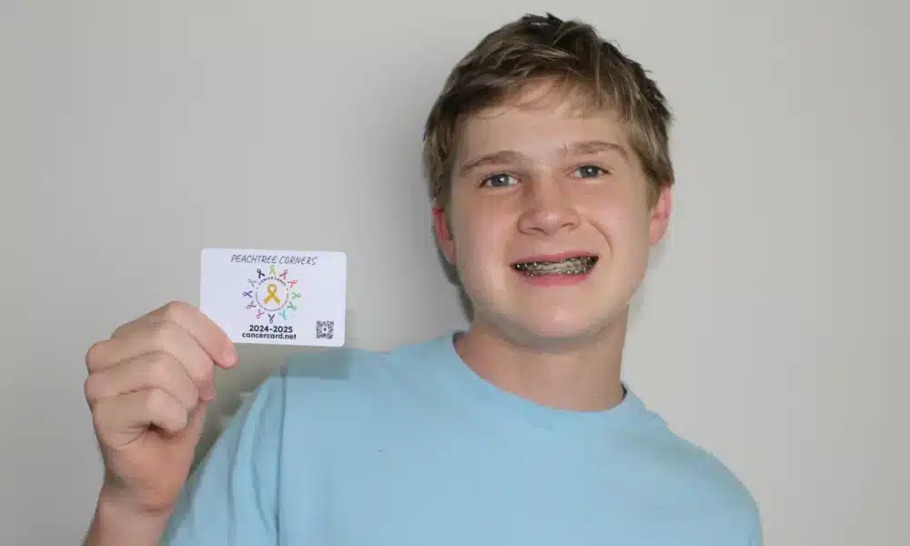 Teen boy holding a card and smiling at the camera