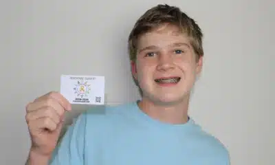 Teen boy holding a card and smiling at the camera