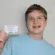 Teen boy holding a card and smiling at the camera