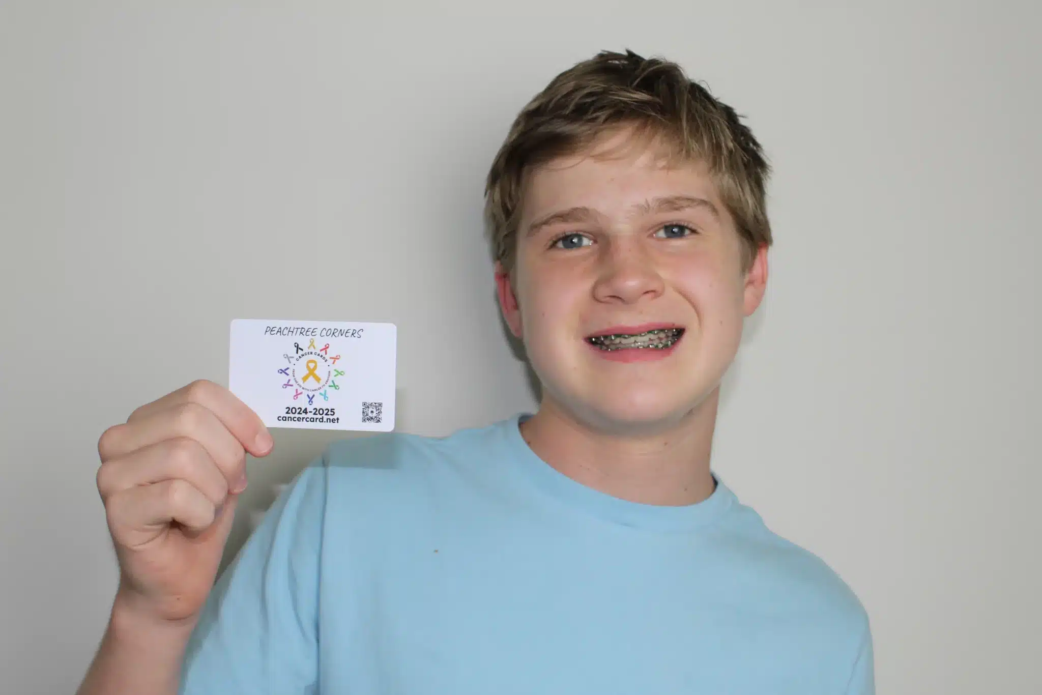 Teen boy holding a card and smiling at the camera