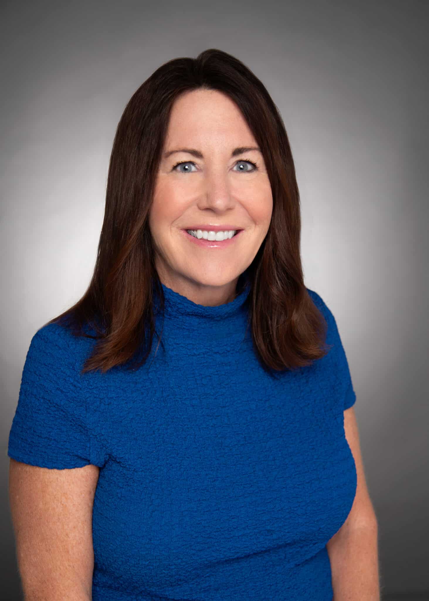 Professional headshot of a brown-haired woman wearing a blue top