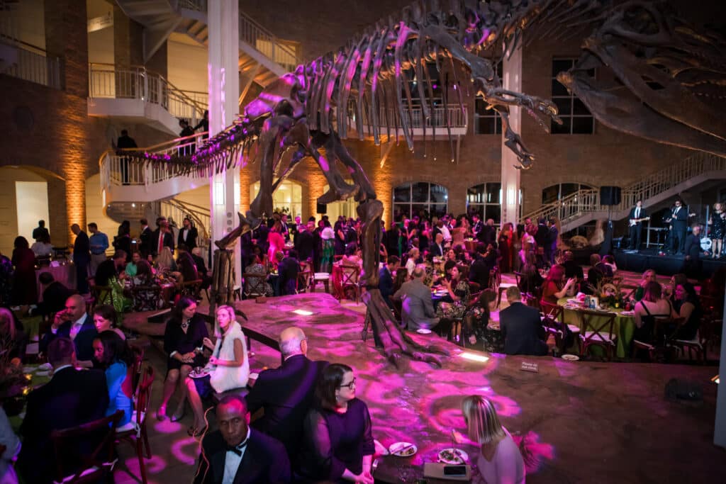 Group of people under purple lighting at a fundraising gala in a natural history museum