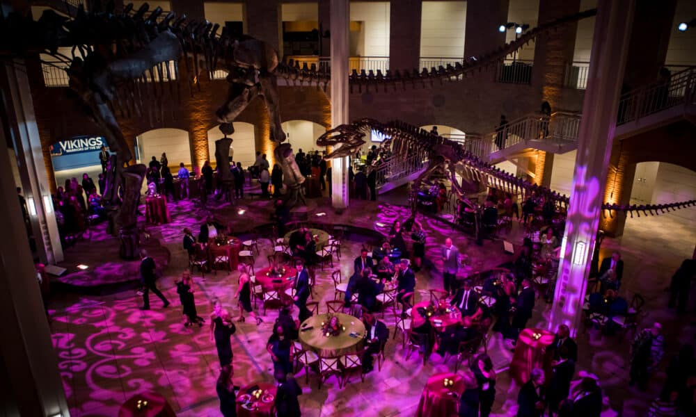 Group of people gathered in a natural history museum at night for a fundraising gala