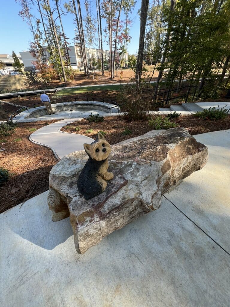 Stone bench with dog statue at Debbie Mason Memorial Garden