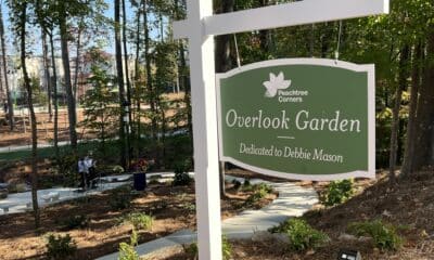 A green sign with white lettering and white post for the Debbie Mason Overlook Garden in Peachtree Corners