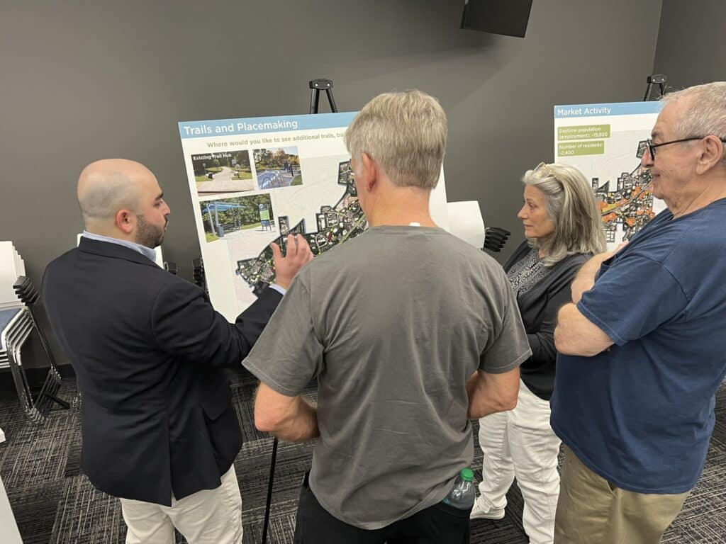 people standing around and looking at map displays at a city meeting