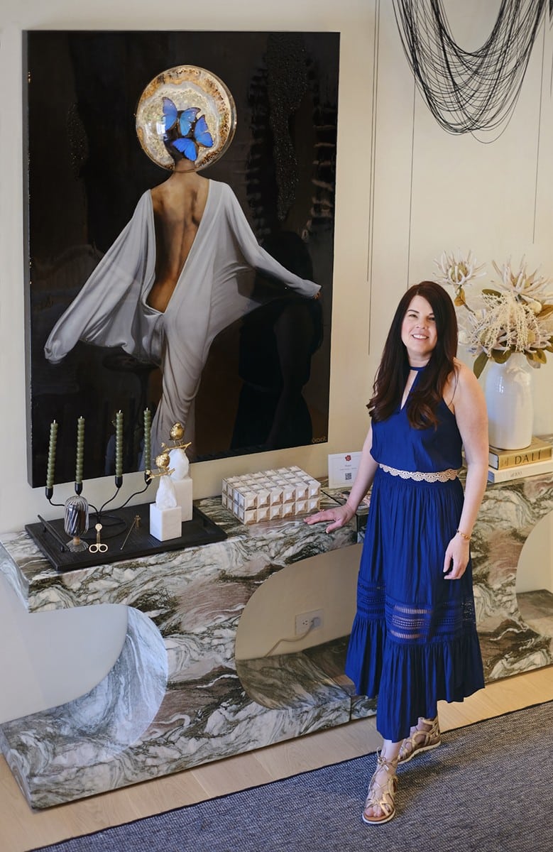 Woman in blue dress standing in front of painting