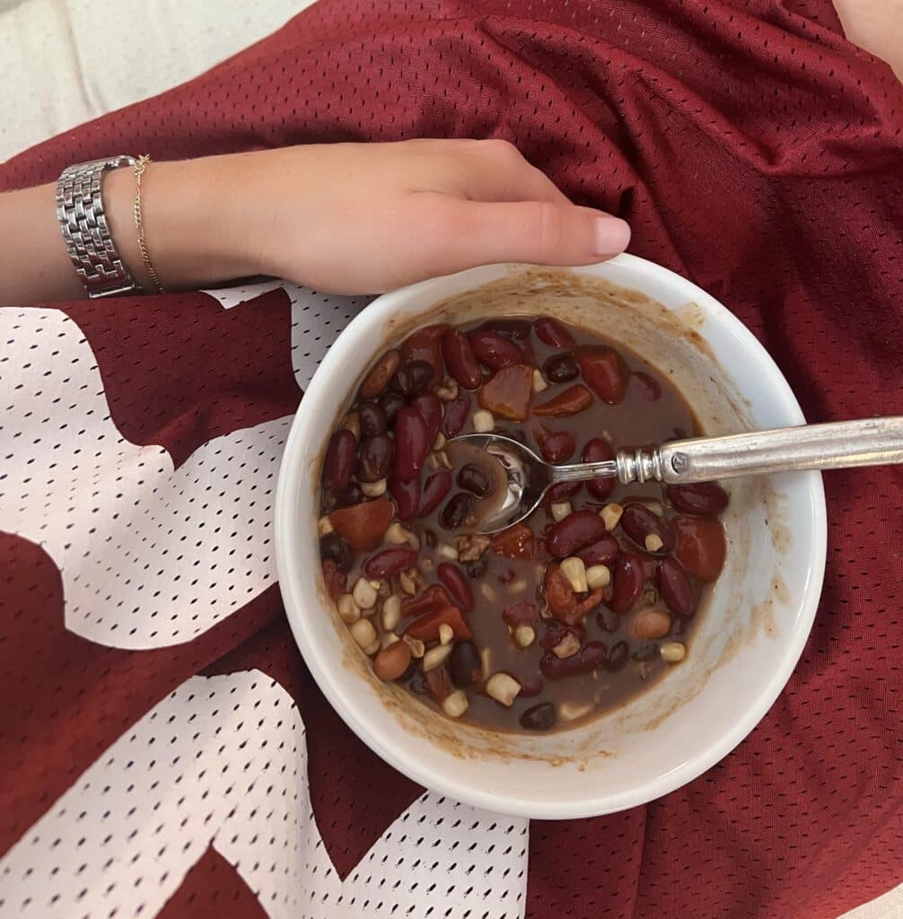 Woman in a football jersey holding a bowl of soup on her lap