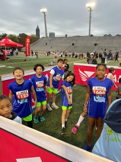 Group of young track cross country students in blue shirts outside at an event.