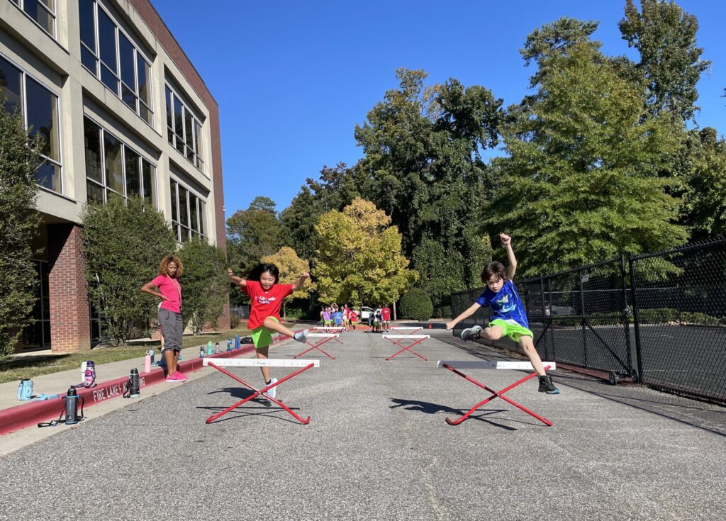 Young students in a parking lot practicing for track events and doing PE.