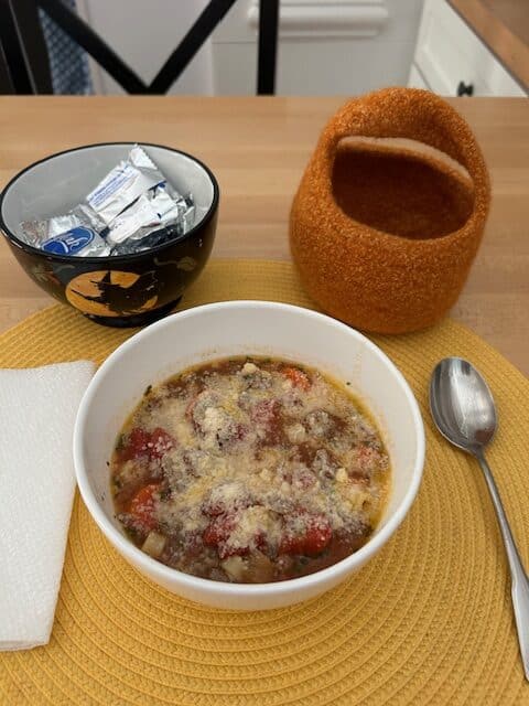 bowl of soup on a table with napkin, spoon and accompaniments 