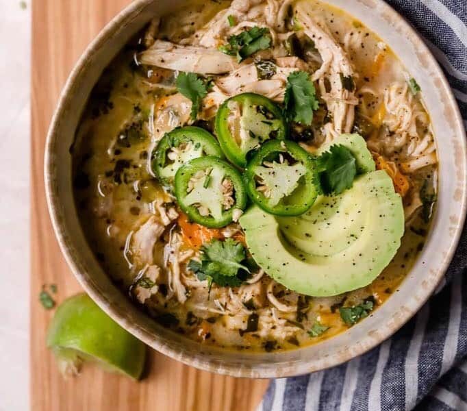 bowl of white chicken chili topped with jalapenos and avocado