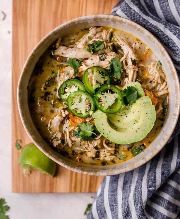 bowl of white chicken chili topped with jalapenos and avocado