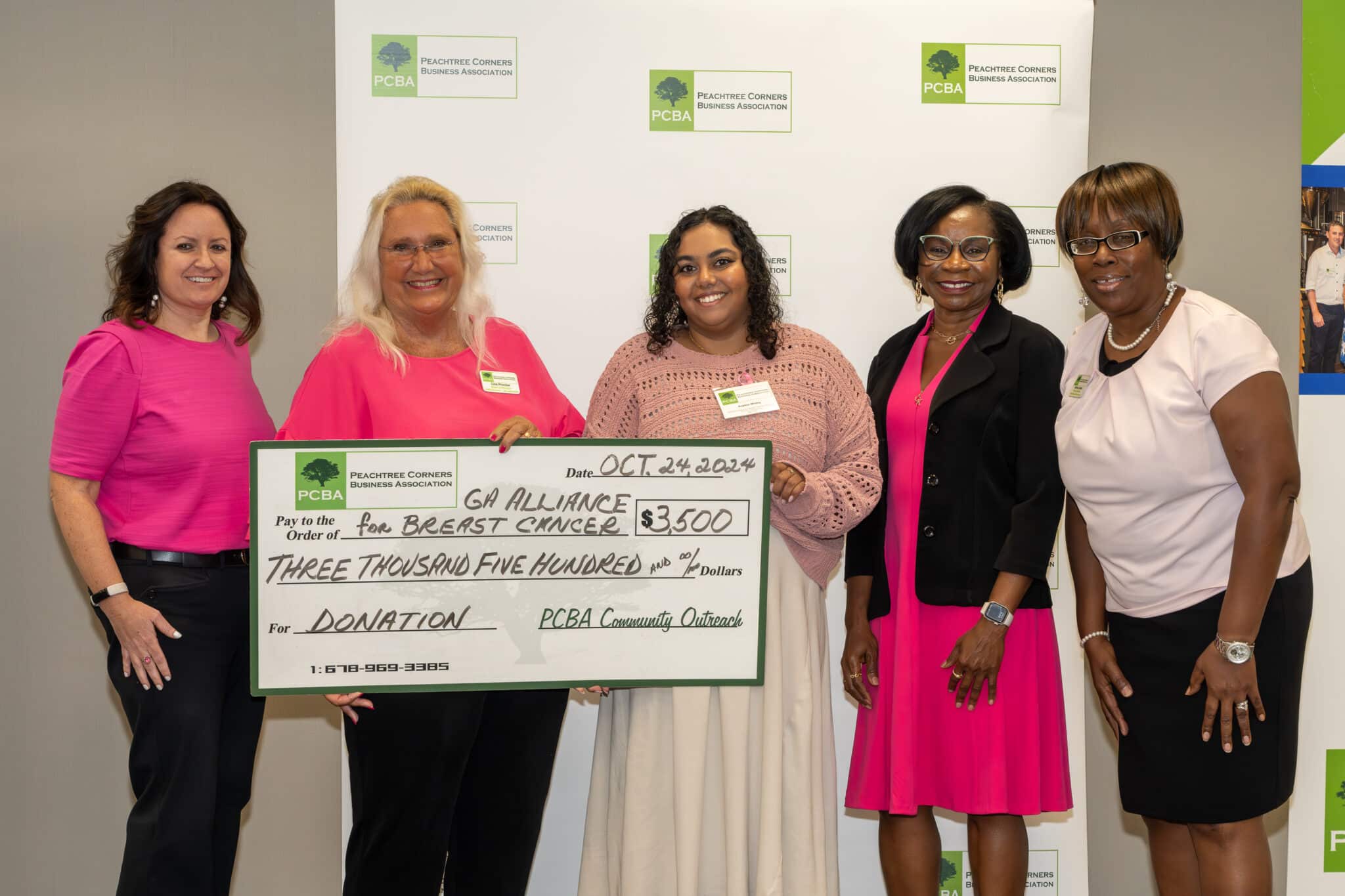 Group of women holding a large check representing a donation from PCBA to GABC