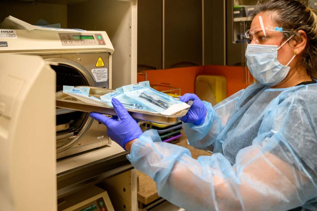 Healthcare worker sterilizing dentistry instruments