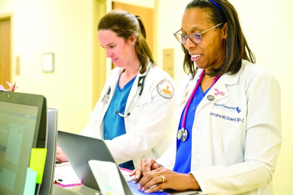 Two female healthcare workers standing at their computers