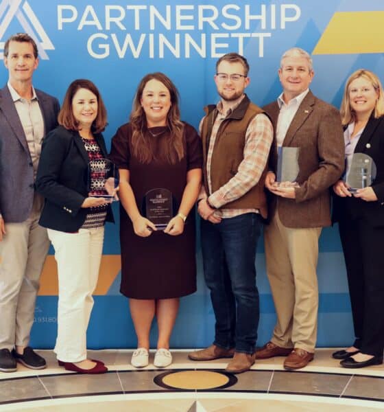 A group of award winners in front of a Partnership Gwinnett sign