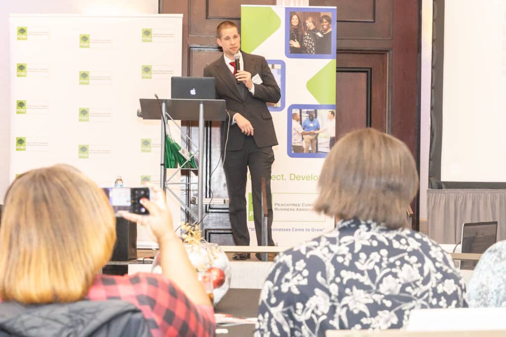 Man in a suit speaking to an audience at an end-of-year business event