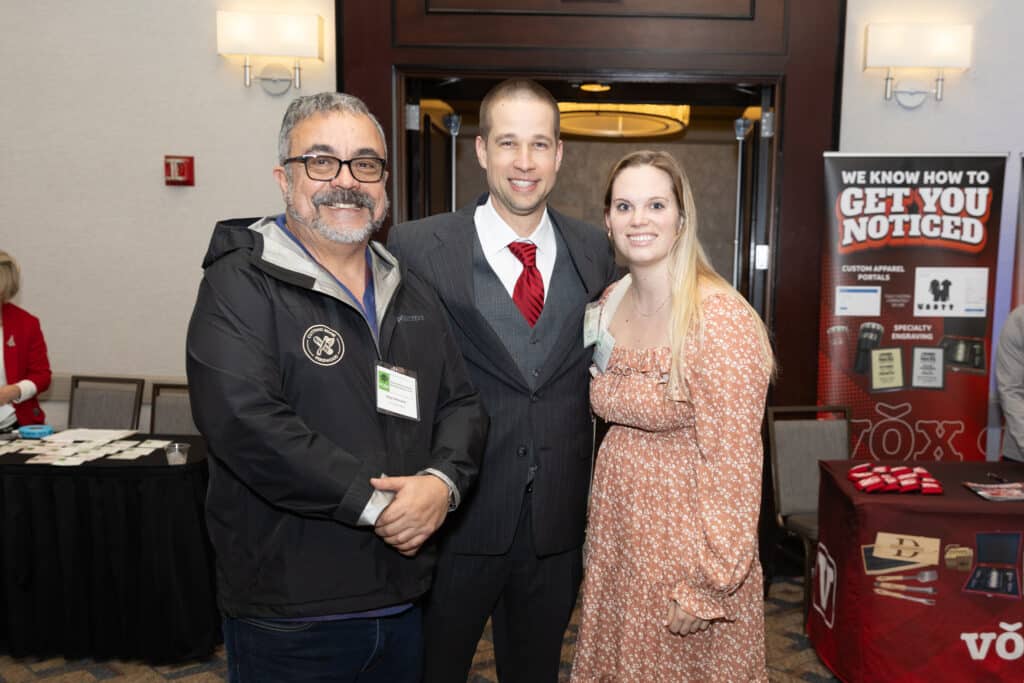 Two men and one woman posing for a photo at an end-of-year business event