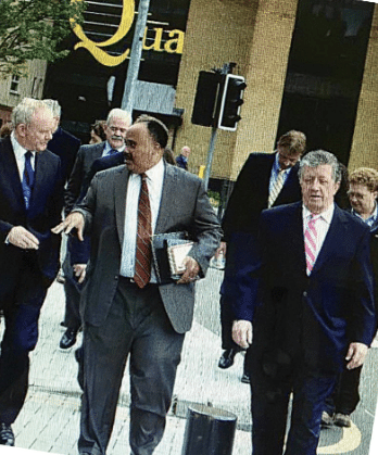 A group of men in suits walking together and talking outdoors