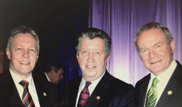 Three white men wearing suits, standing together and smiling for the photo