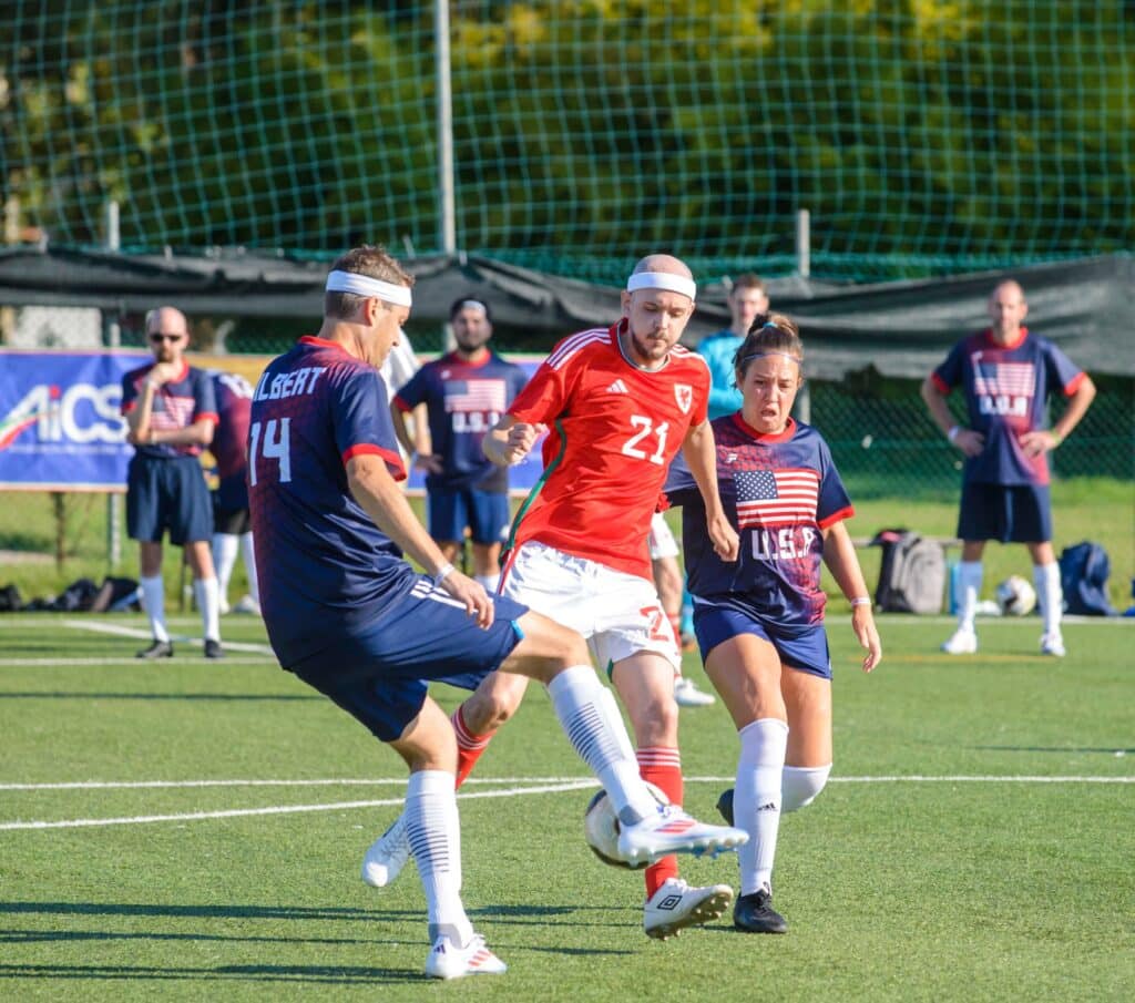 Soccer players in the middle of a match. One team is wearing blue, the other red and white.