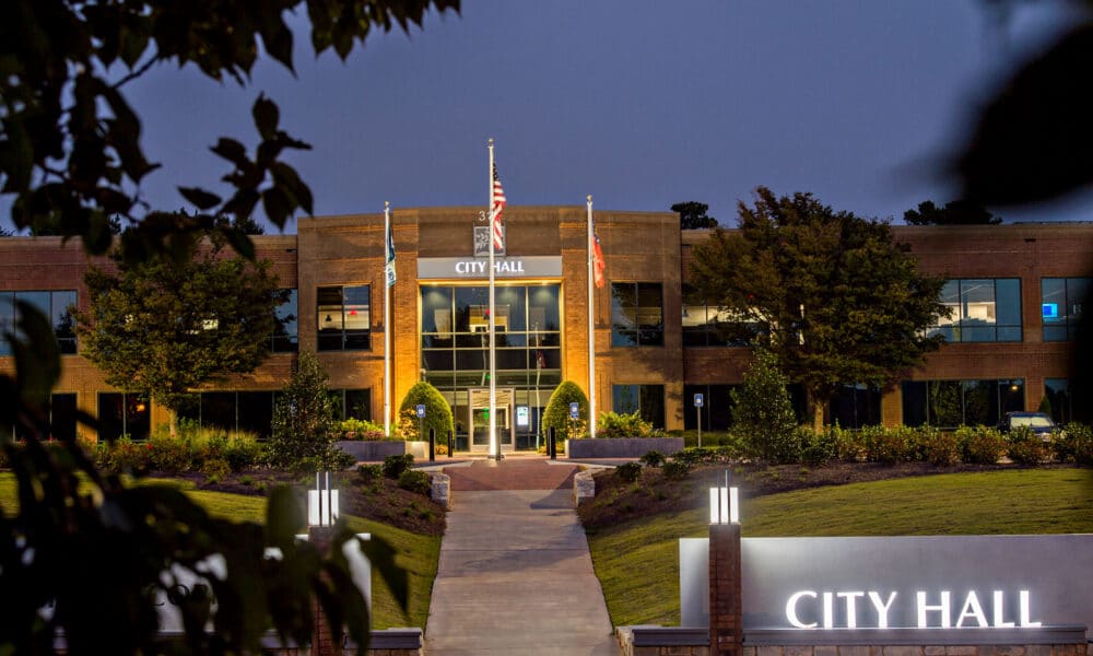 Peachtree Corners City Hall in the evening with flag display, signage and lights.