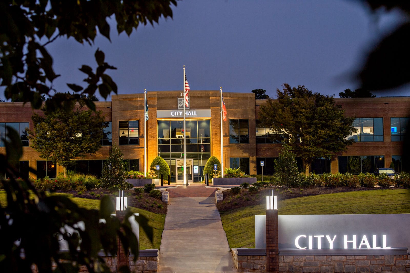 Peachtree Corners City Hall in the evening with flag display, signage and lights.