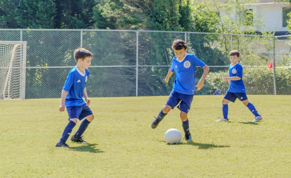 Kids in blue jerseys playing soccer