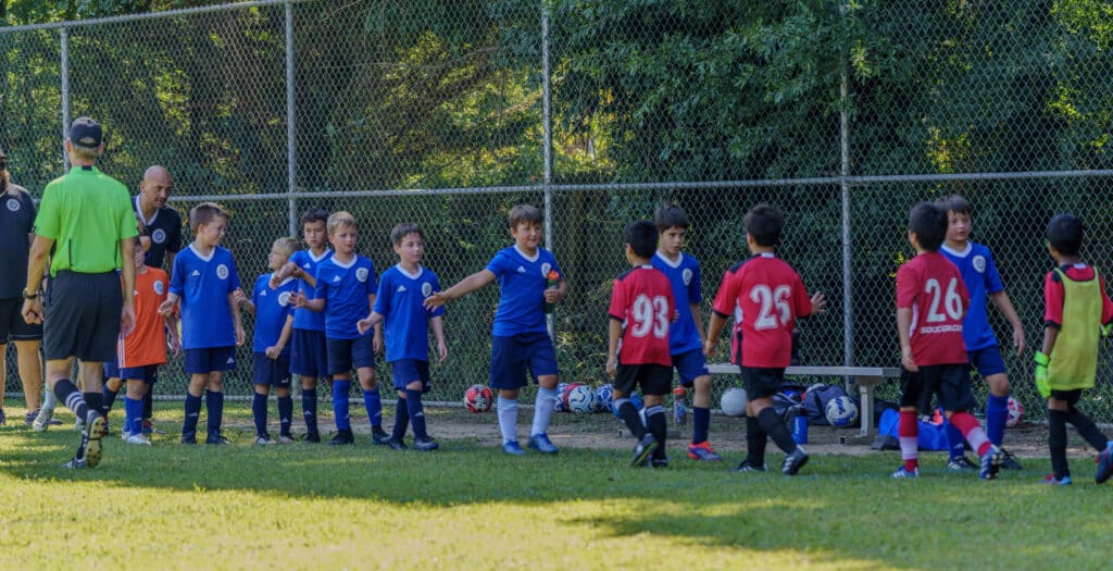 Kids from opposing soccer teams lining up to high five each other after a match