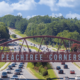 Aerial photo of the Peachtree Corners pedestrian bridge with trees in the background, businesses alongside, and cars driving on the six-lane road beneath it.