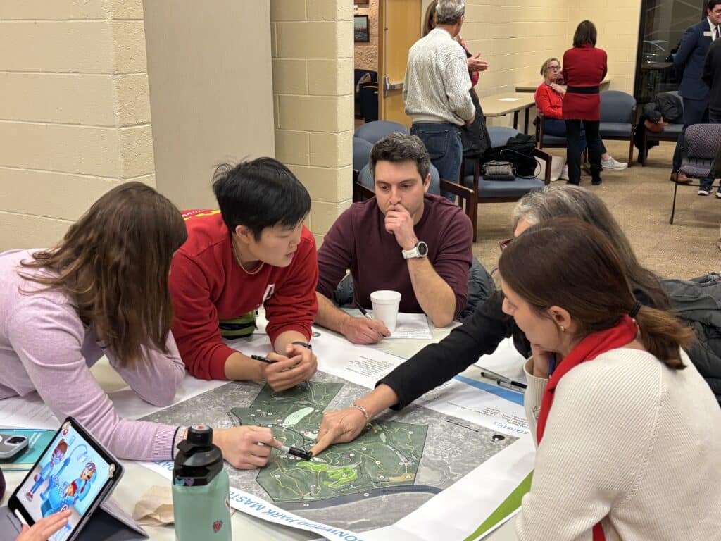 A group of people sitting around a table at a community meeting, looking over proposed plans for Simpsonwood Park