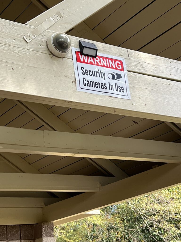 Security camera on a wood beam in a pavilion next to a soccer field