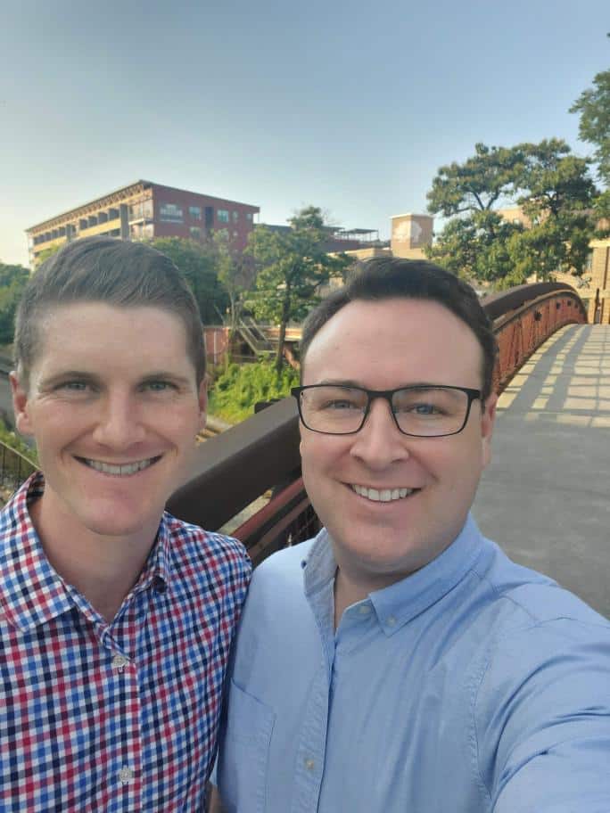 Two white men in button down shirts taking a selfie together outdoors