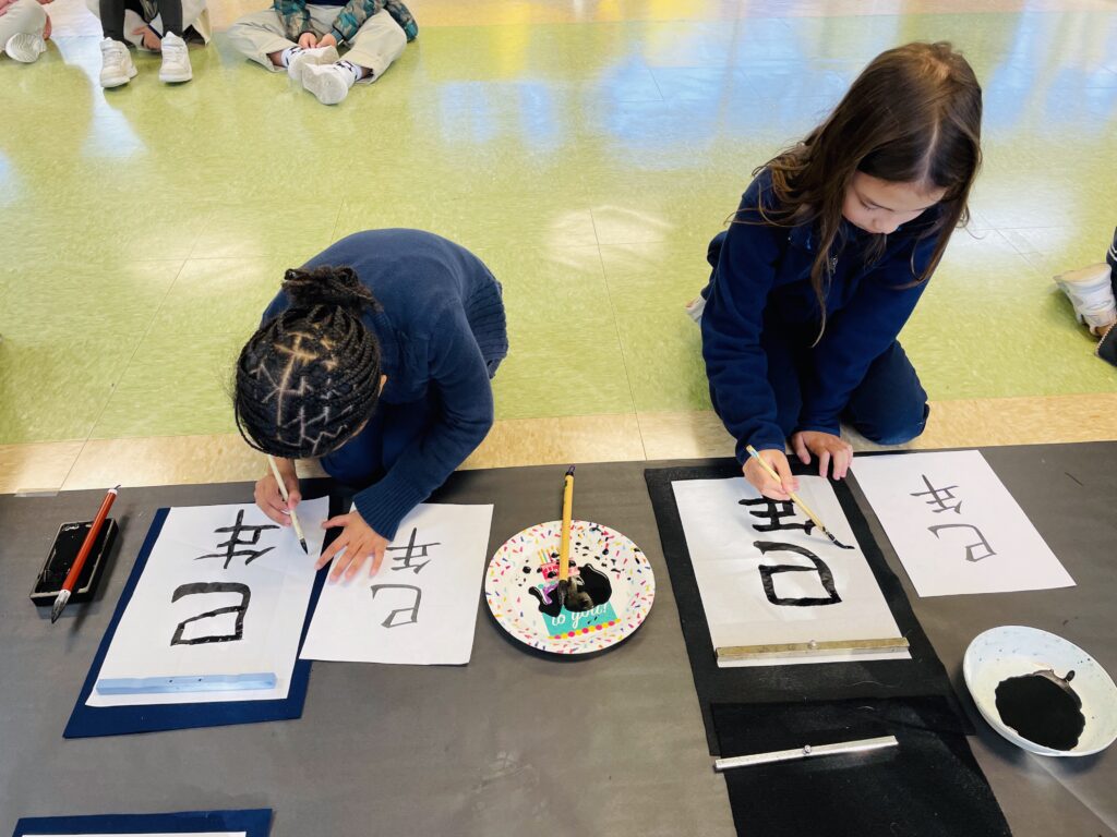 Students practicing Japanese calligraphy with brush and ink