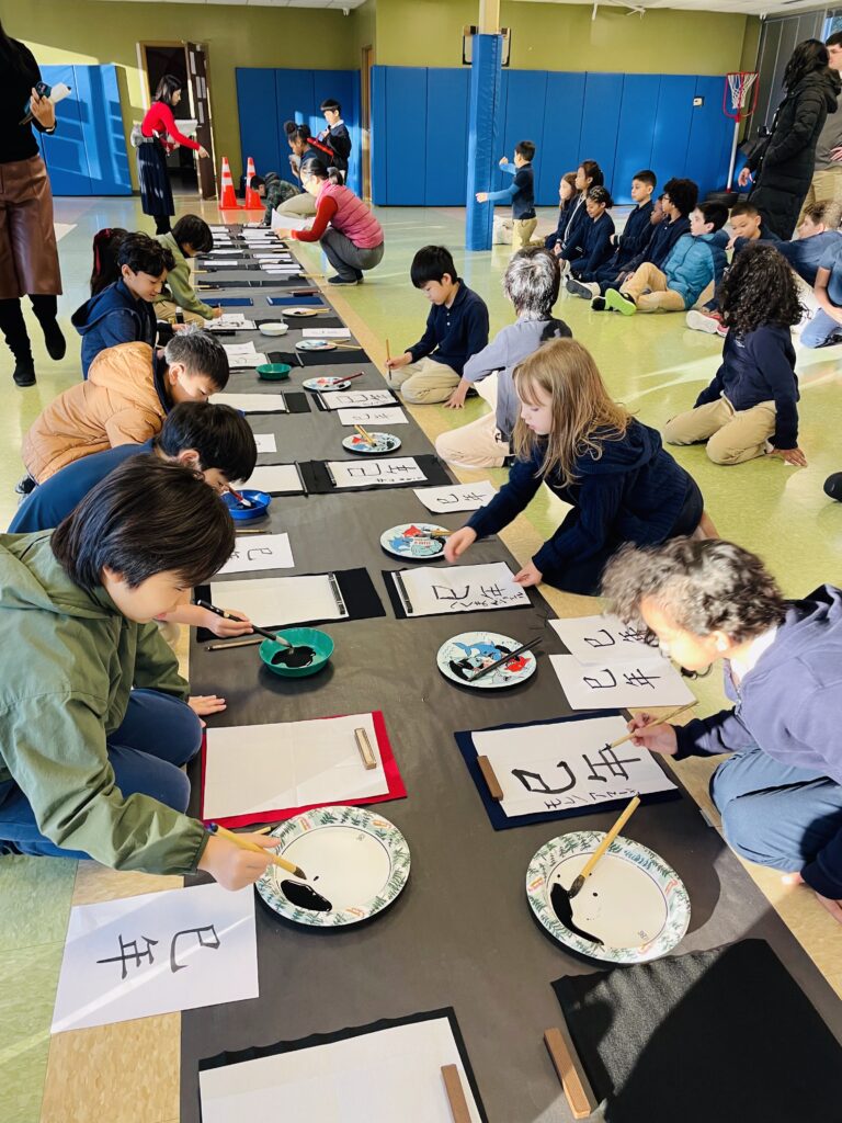 Students practicing Japanese calligraphy with brush and ink