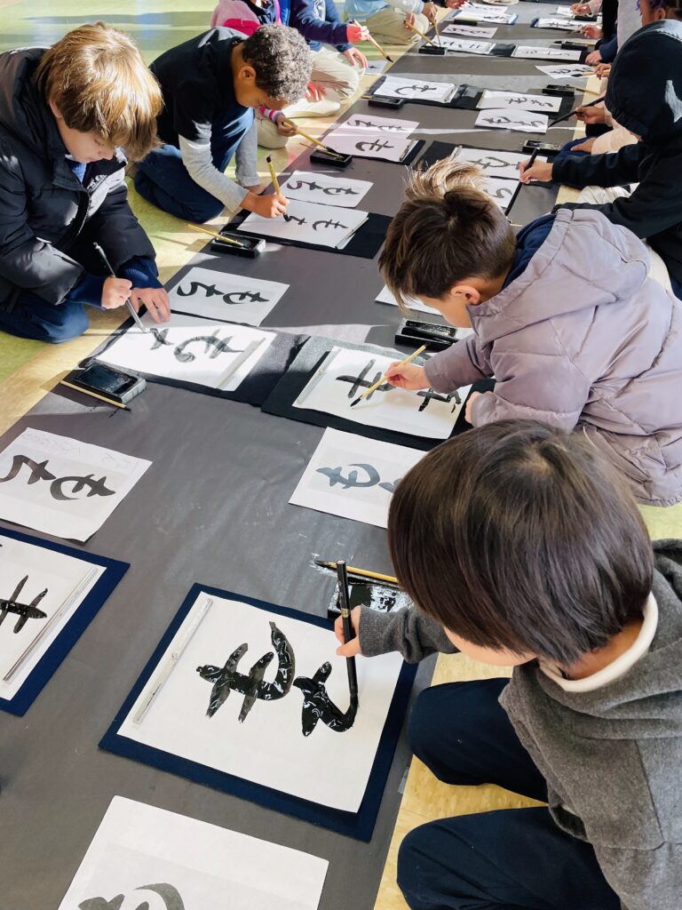 Students practicing Japanese calligraphy with brush and ink