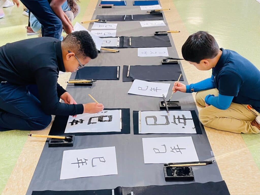 Students practicing Japanese calligraphy with brush and ink