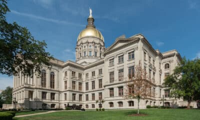 Georgia State Capitol building with green grass in front, trees on either side and blue sky overhead.