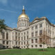 Georgia State Capitol building with green grass in front, trees on either side and blue sky overhead.