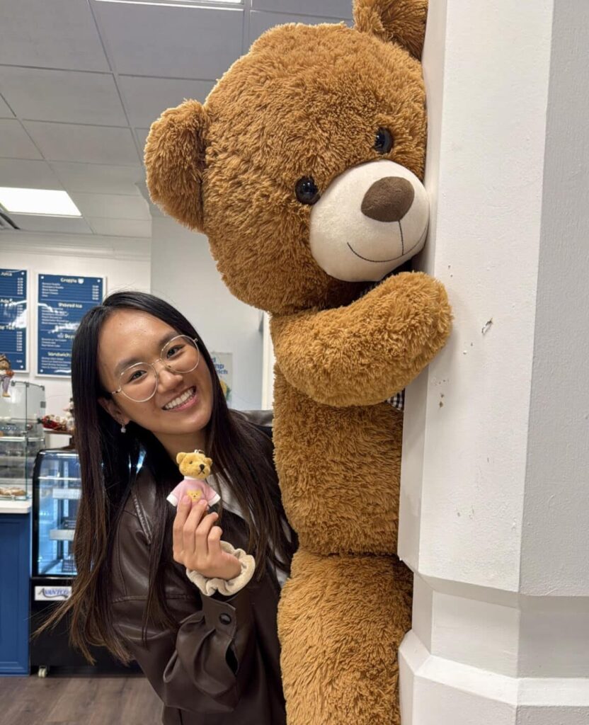 Young Asian woman with long hair and glasses, smiling with a giant teddy bear at a local Pho restaurant