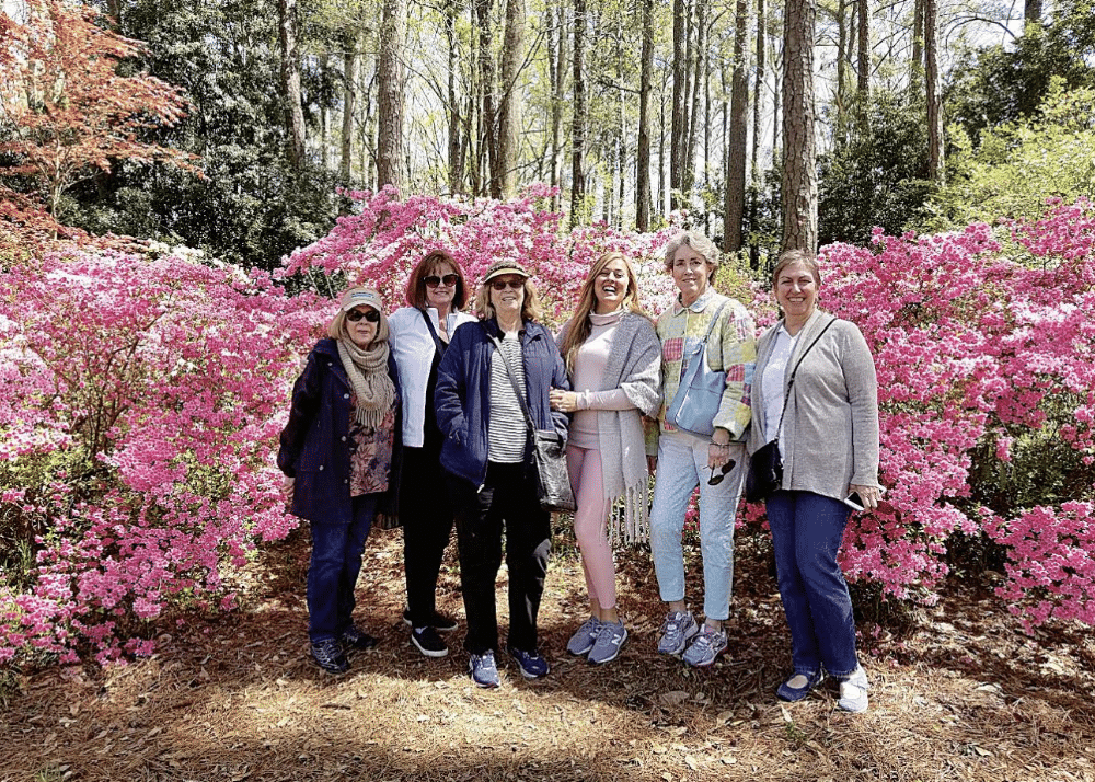 Group of women posing for a photo in front of large pink azalea bushes at Calloway Gardens