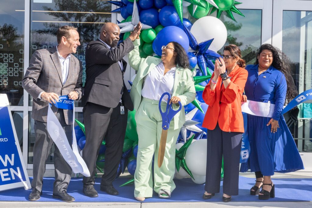 People in front of a new Fifth Third Bank location celebrating with a ribbon cutting and balloons