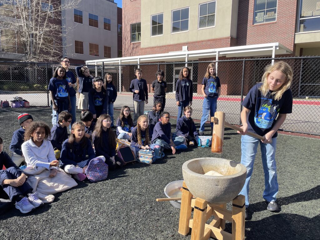 Students at a dual-language school pounding rice with a wooden mallet at Japanese new year event.