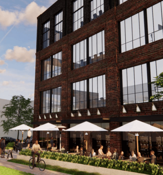 Rendering of a three story building with outdoor cafe tables and umbrellas along the side of it.